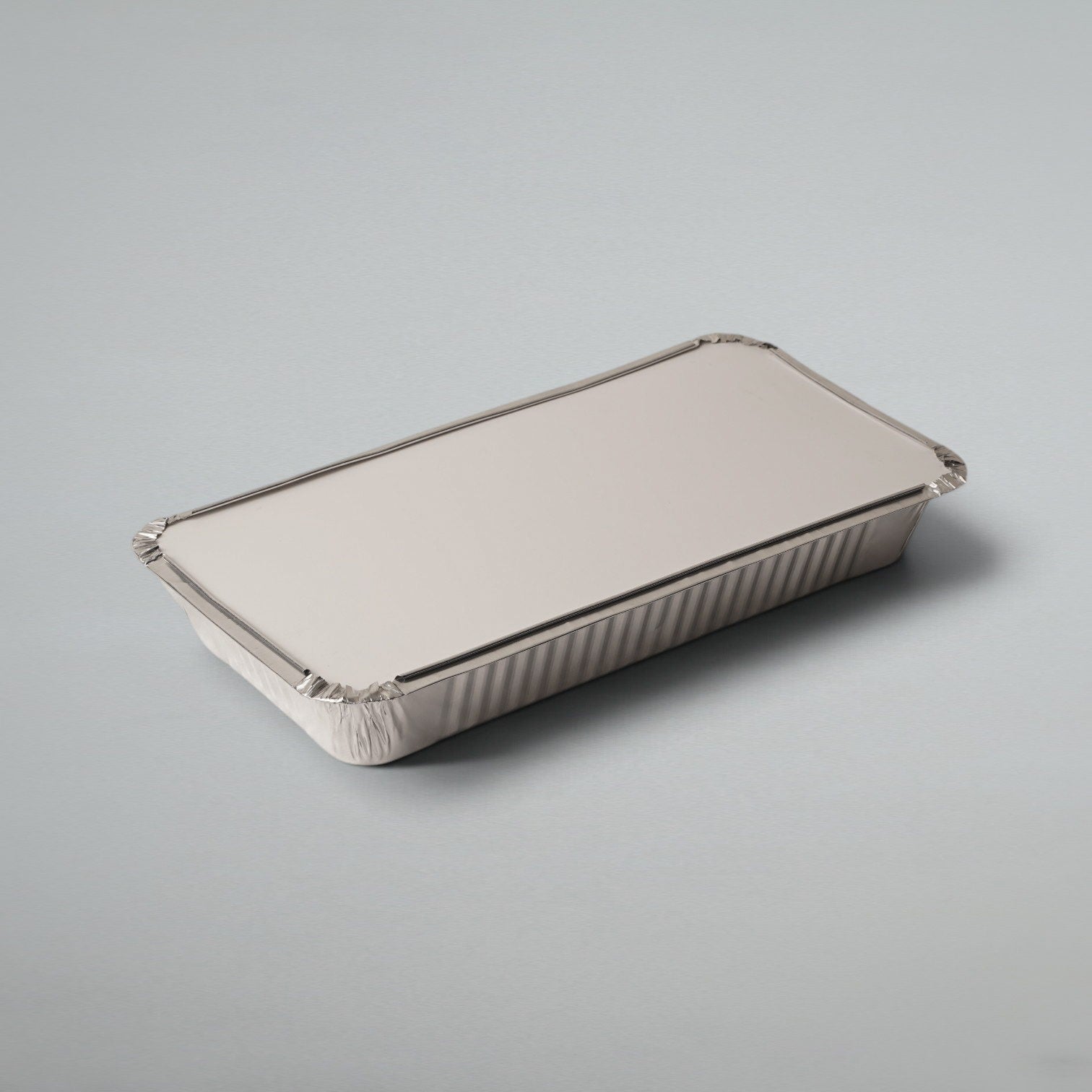 A rectangular disposable aluminum foil tray with a matching lid, shown on a neutral light gray background.