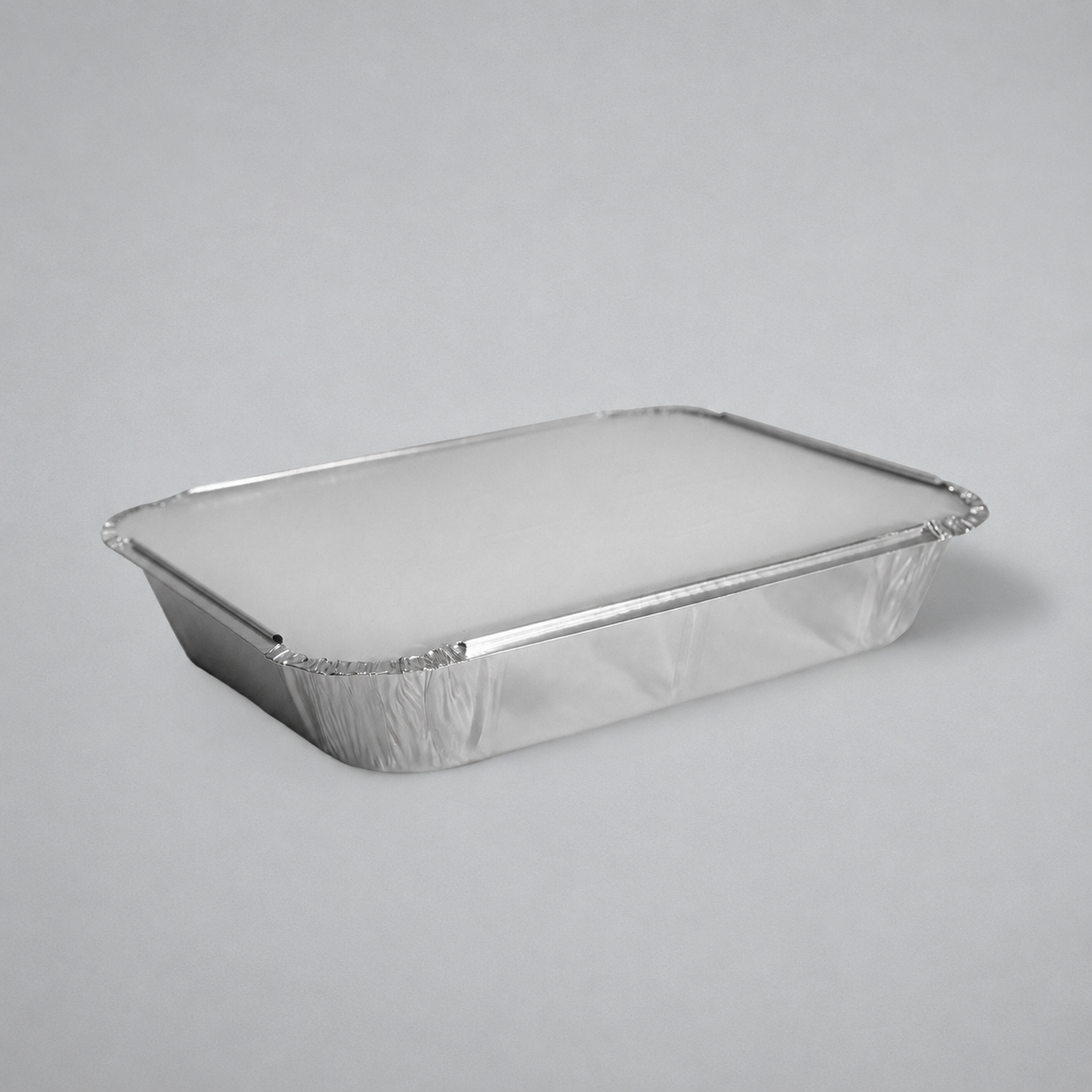 7x9 A rectangular aluminum foil tray with a crimped edge and a translucent lid, shown on a neutral gray background.