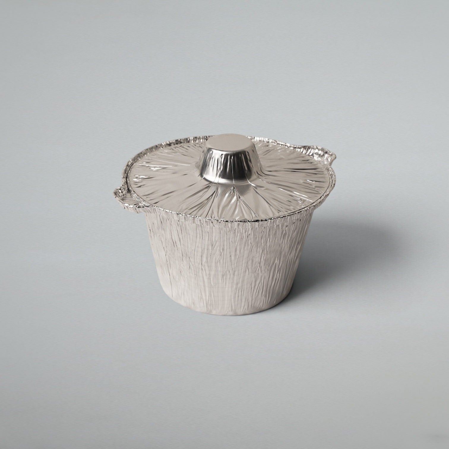 Angled view of a round aluminium food pot with fitted foil lid for takeaway and catering use.