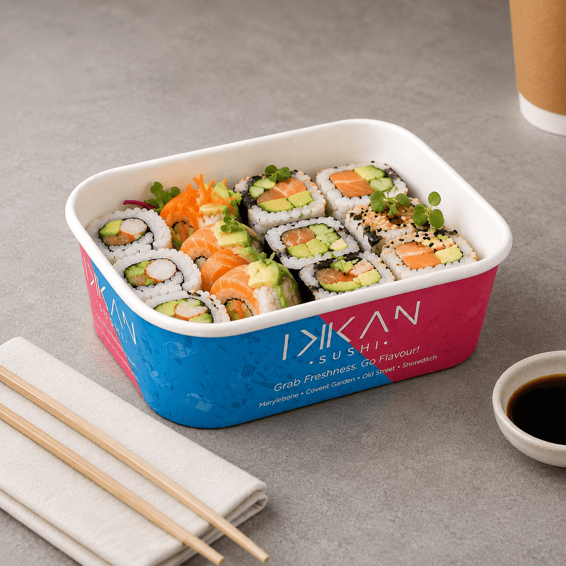 Ikkan Sushi branded takeaway food container filled with fresh sushi rolls, salmon, avocado and cucumber.