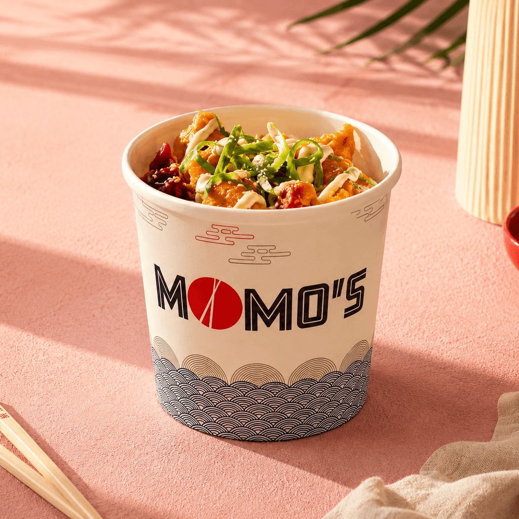 Momo’s branded takeaway food container filled with an Asian-inspired dish, presented in a warm restaurant setting.