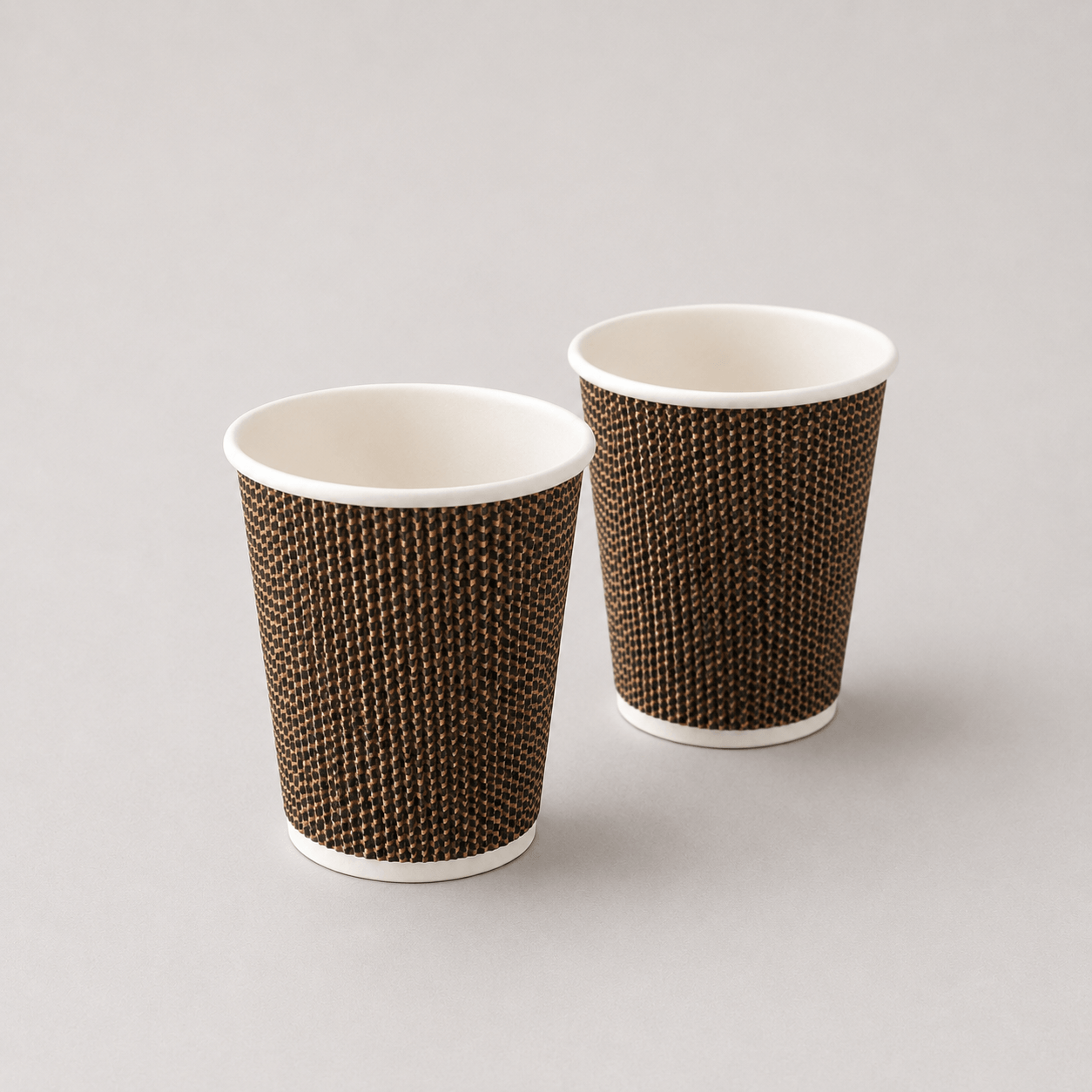 Two disposable paper cups with a brown and black textured pattern and white interiors, shown on a light gray background.