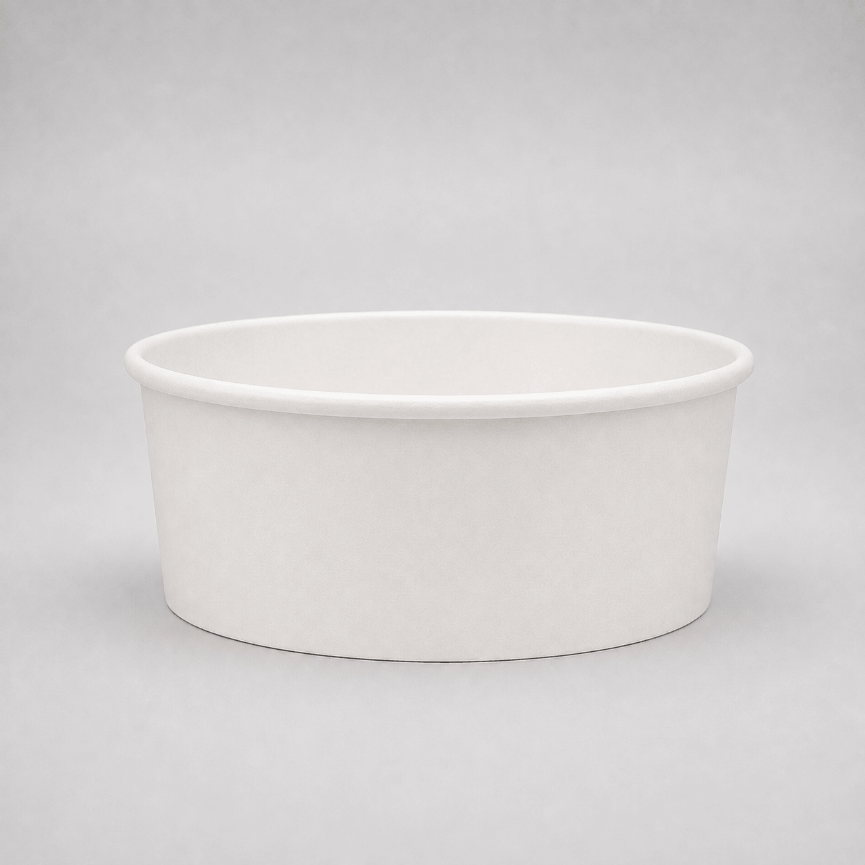 A plain white paper cup or shallow bowl-shaped container photographed on a light gray studio background.