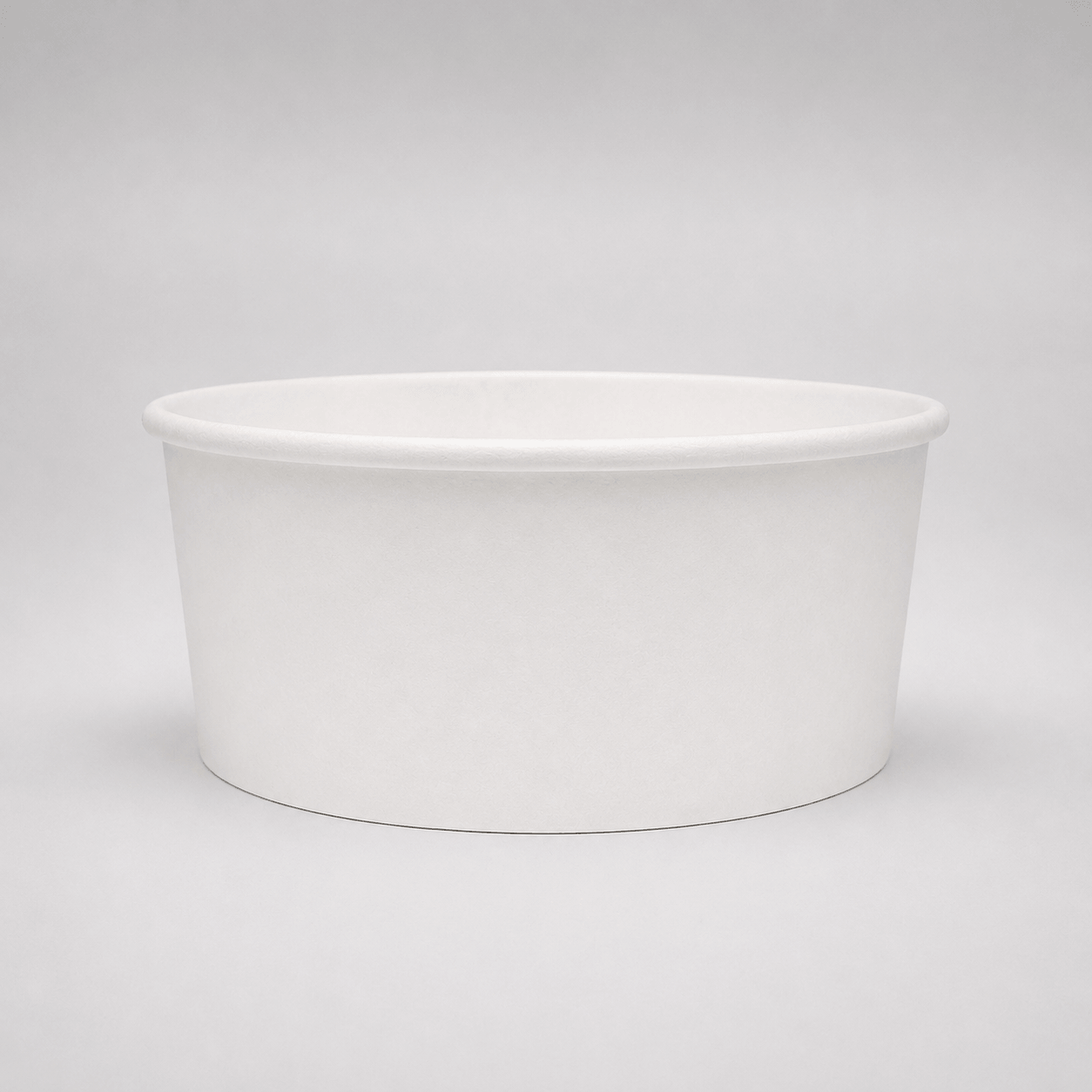A plain white paper cup or shallow bowl-shaped container photographed on a light gray studio background.